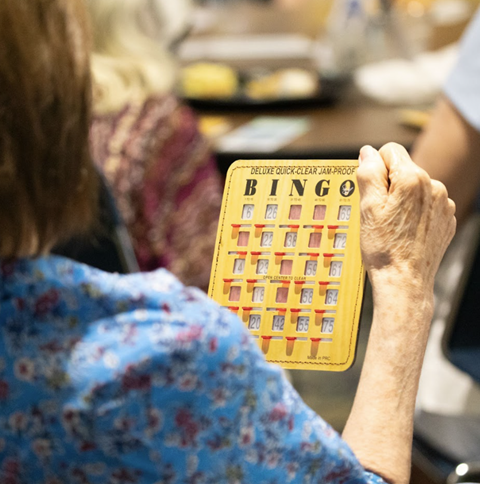 A woman holds up a BINGO game card.